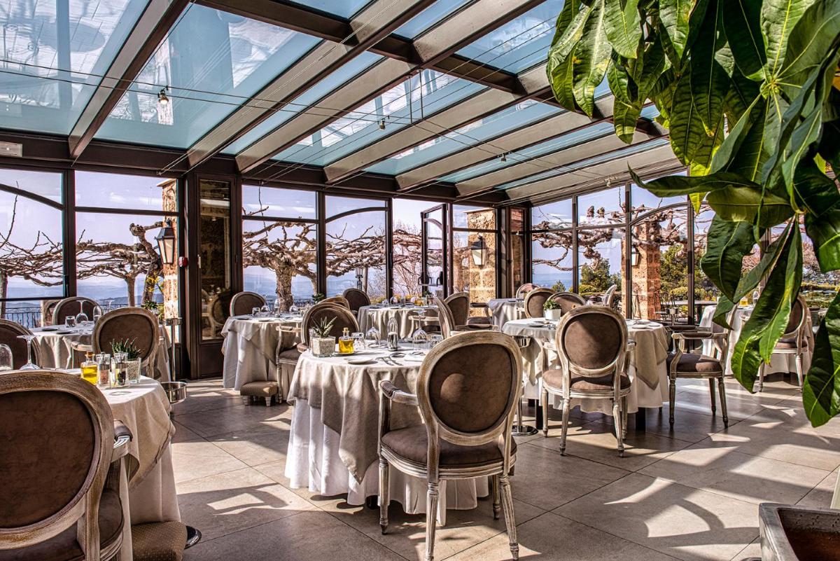 un restaurant avec des tables, des chaises et des fenêtres dans l'établissement La Bastide De Tourtour Hotel & Spa, à Tourtour