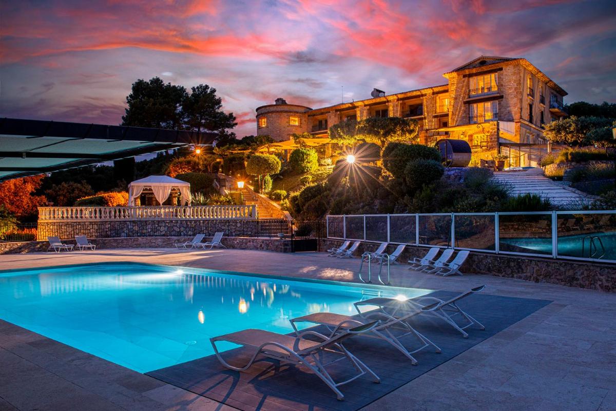une piscine avec des chaises et un bâtiment en arrière-plan dans l'établissement La Bastide De Tourtour Hotel & Spa, à Tourtour