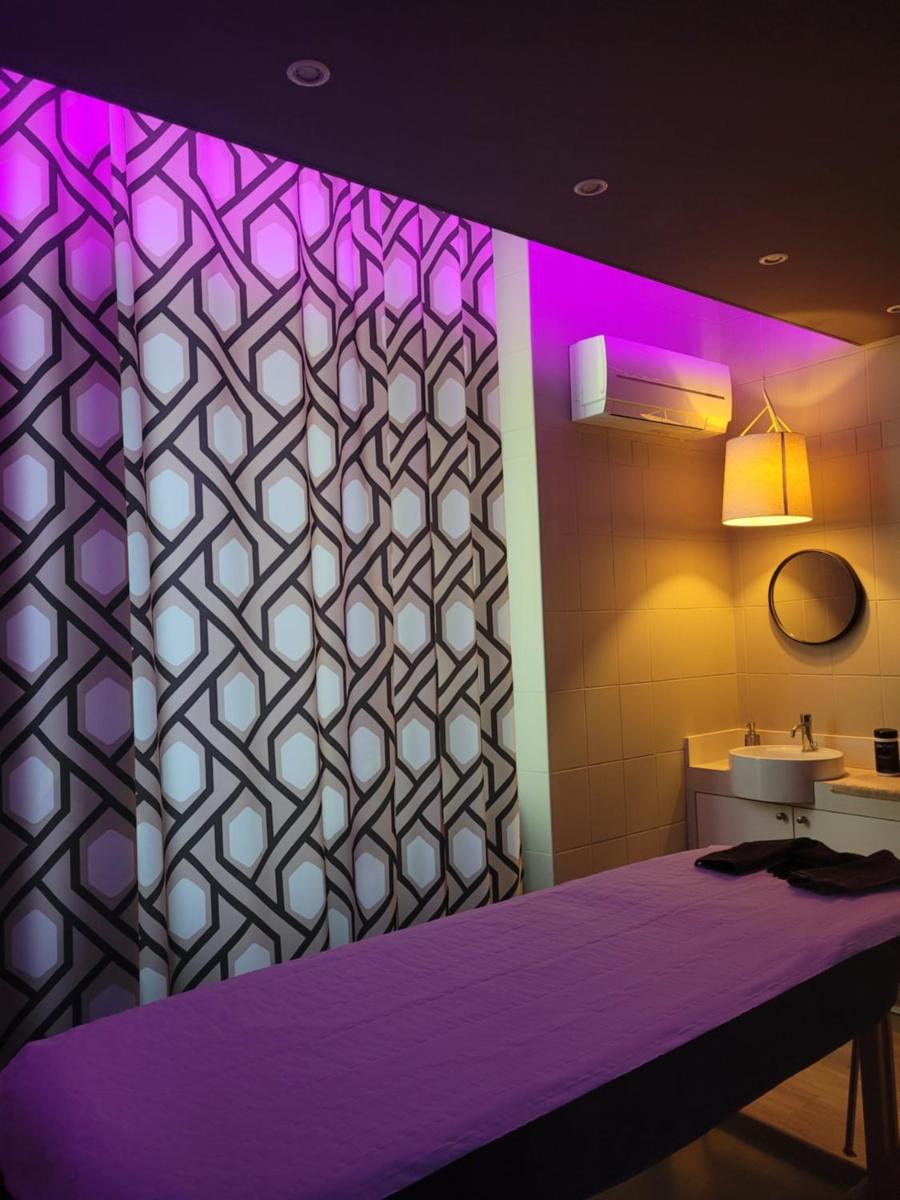 La salle de bains est pourvue d'un lavabo et de murs violets et blancs. dans l'établissement Hôtel Cosmos & Spa, à Contrexéville
