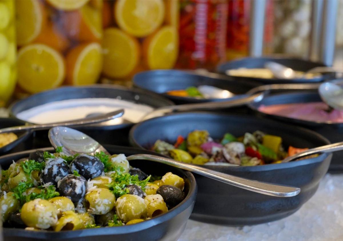 a bunch of dishes of food in pans with spoons at Holiday Inn Chennai OMR IT Expressway by IHG in Chennai