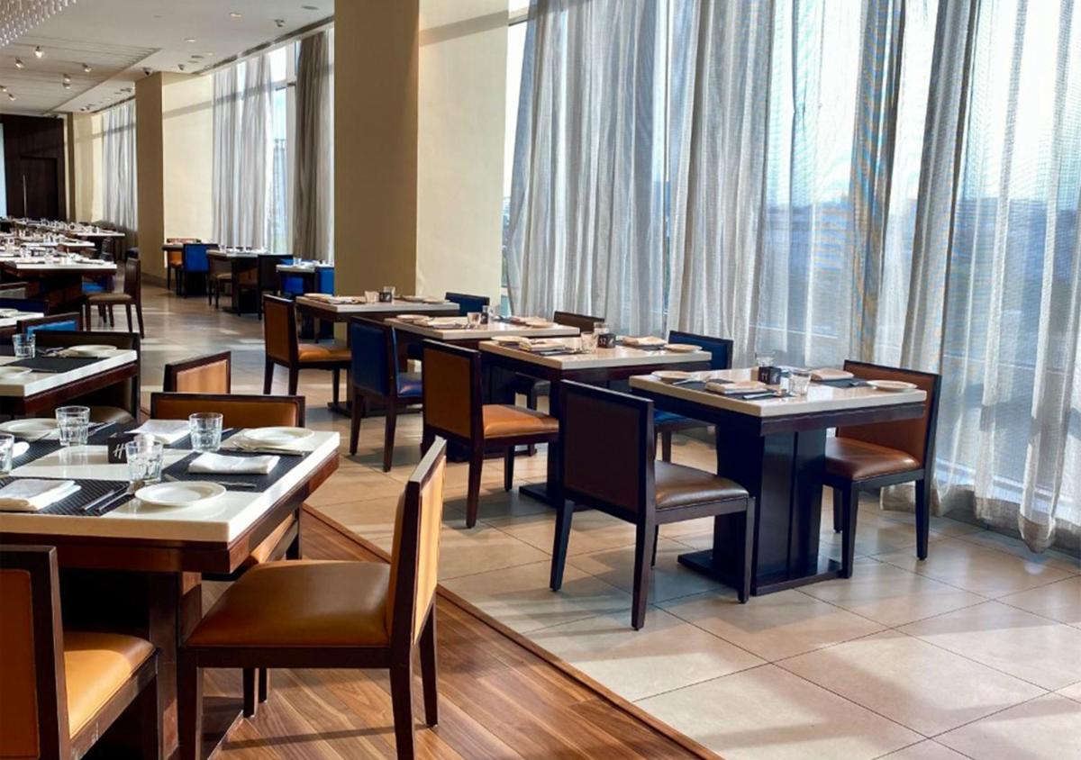 a dining room with tables and chairs and windows at Holiday Inn Chennai OMR IT Expressway by IHG in Chennai