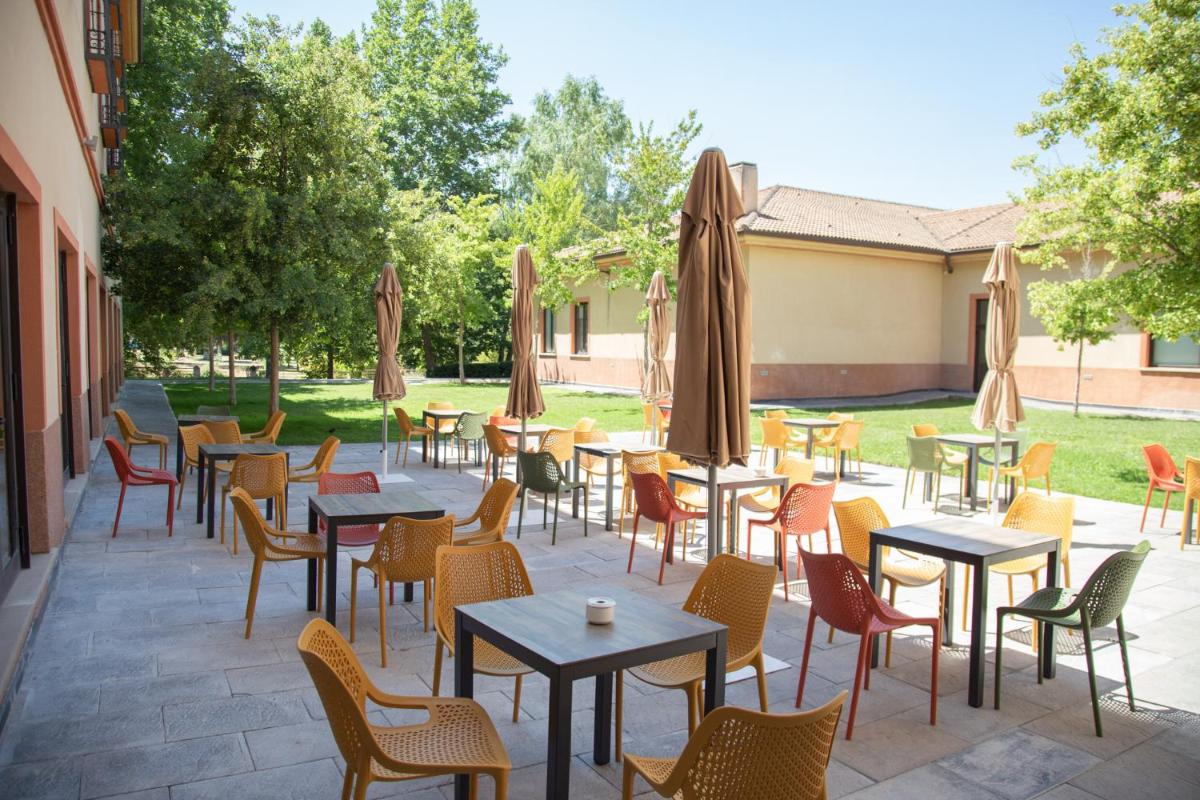 Un patio con mesas, sillas y sombrillas. en Hotel Real Balneario Carlos III, en Trillo