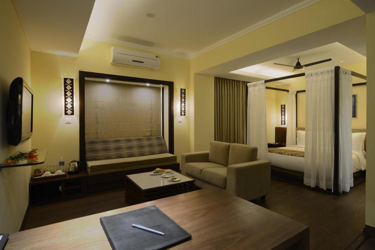 a living room with a couch and a room with a bed at Deltin Suites in Candolim
