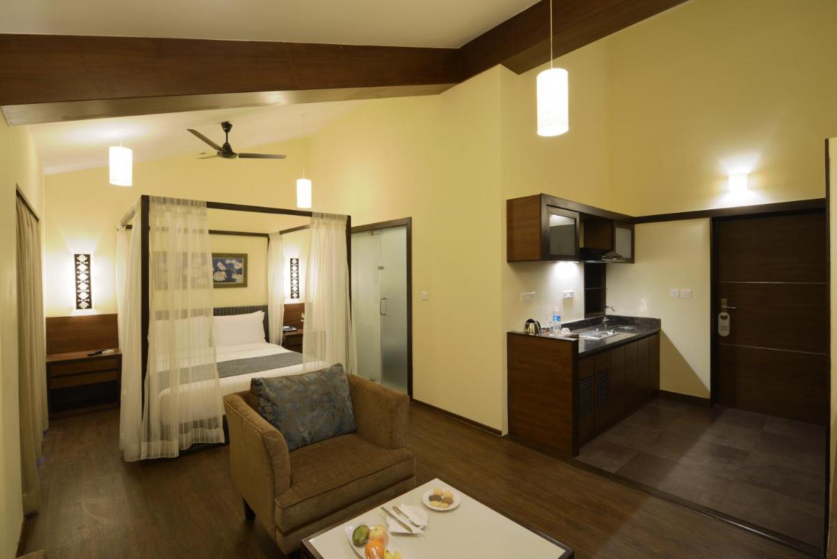 a room with a bed and a couch and a chair at Deltin Suites in Candolim