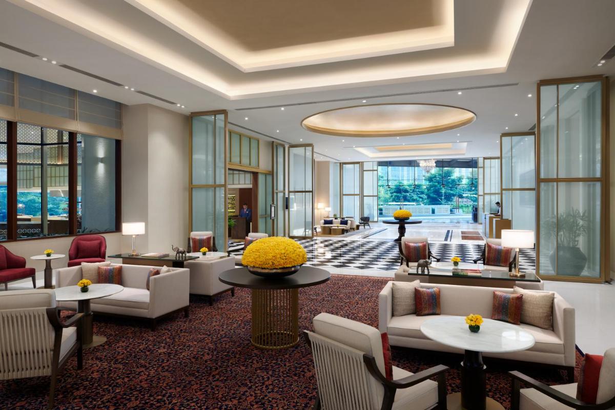 a hotel lobby with couches and tables and windows at The Leela Bhartiya City Bengaluru in Bengaluru a hotel lobby with couches and tables and windows at The Leela Bhartiya City Bengaluru in Bengaluru
