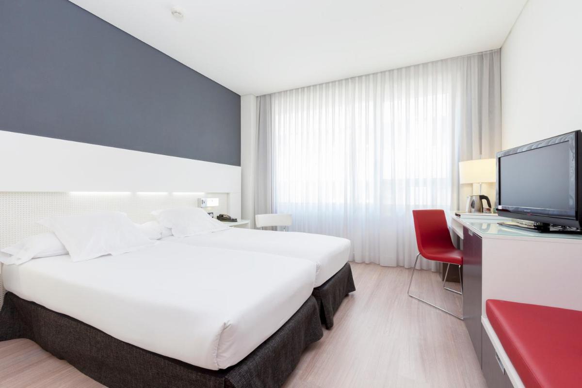Habitación de hotel con cama blanca grande y TV. en Axor Feria, en Madrid