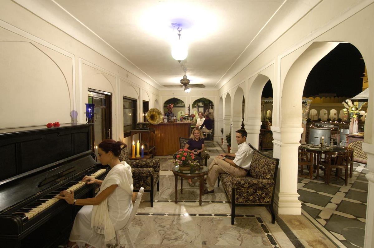 a group of people sitting in a room with a piano at The Raj Palace (Small Luxury Hotels of the World) in Jaipur
