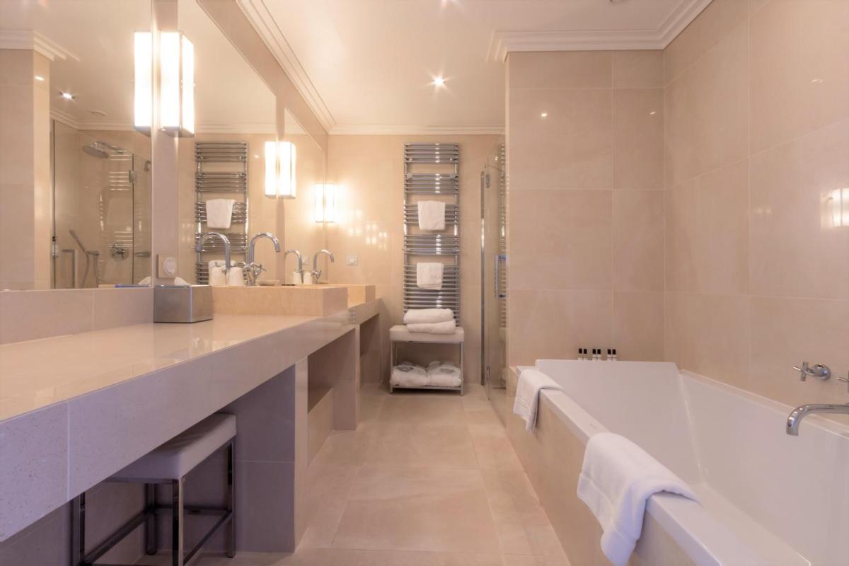 une salle de bain avec une grande baignoire et un grand miroir dans l'établissement Hôtel Les Mouettes - Teritoria, à Ajaccio
