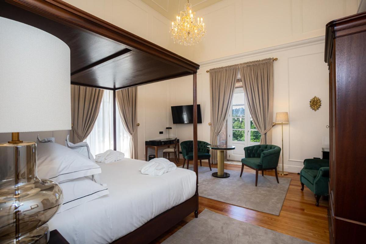 um quarto com uma cama grande, uma escrivaninha e cadeiras em Solar do Requeijo by Luna Hotels & Resorts em Arcos de Valdevez