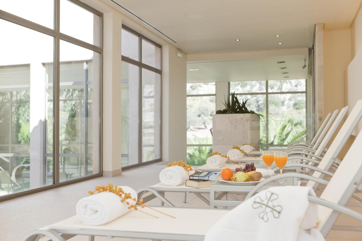 un comedor con sillas blancas y una mesa con fruta. en L’Hermitage Hotel & Spa, en Orient