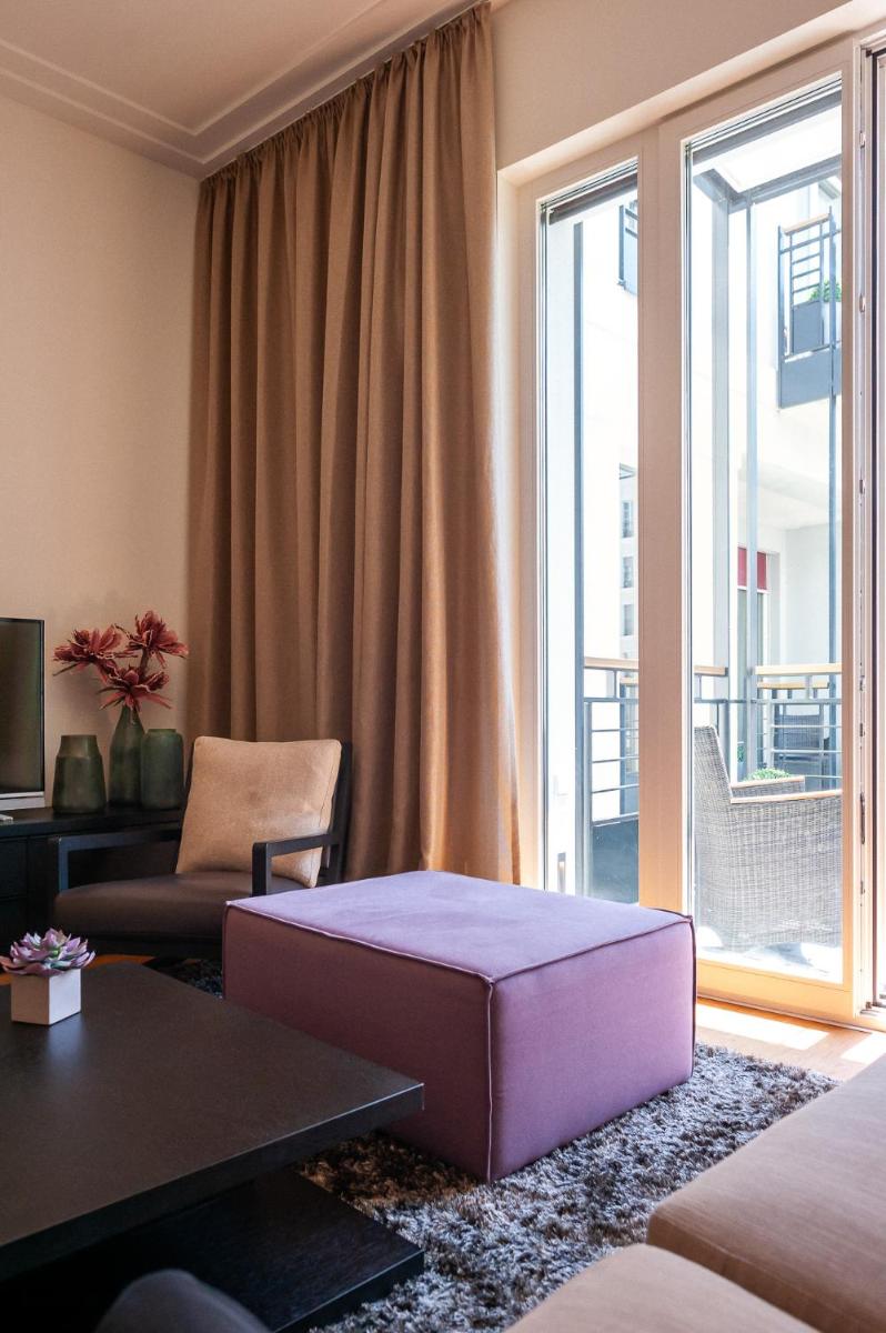 ein Wohnzimmer mit einer lila Ottomane vor einem Fenster in der Unterkunft The Wellem Residences in Düsseldorf