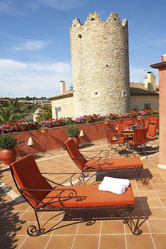 un patio con sillas y un edificio con una torre en Hotel Sa Calma, en Begur