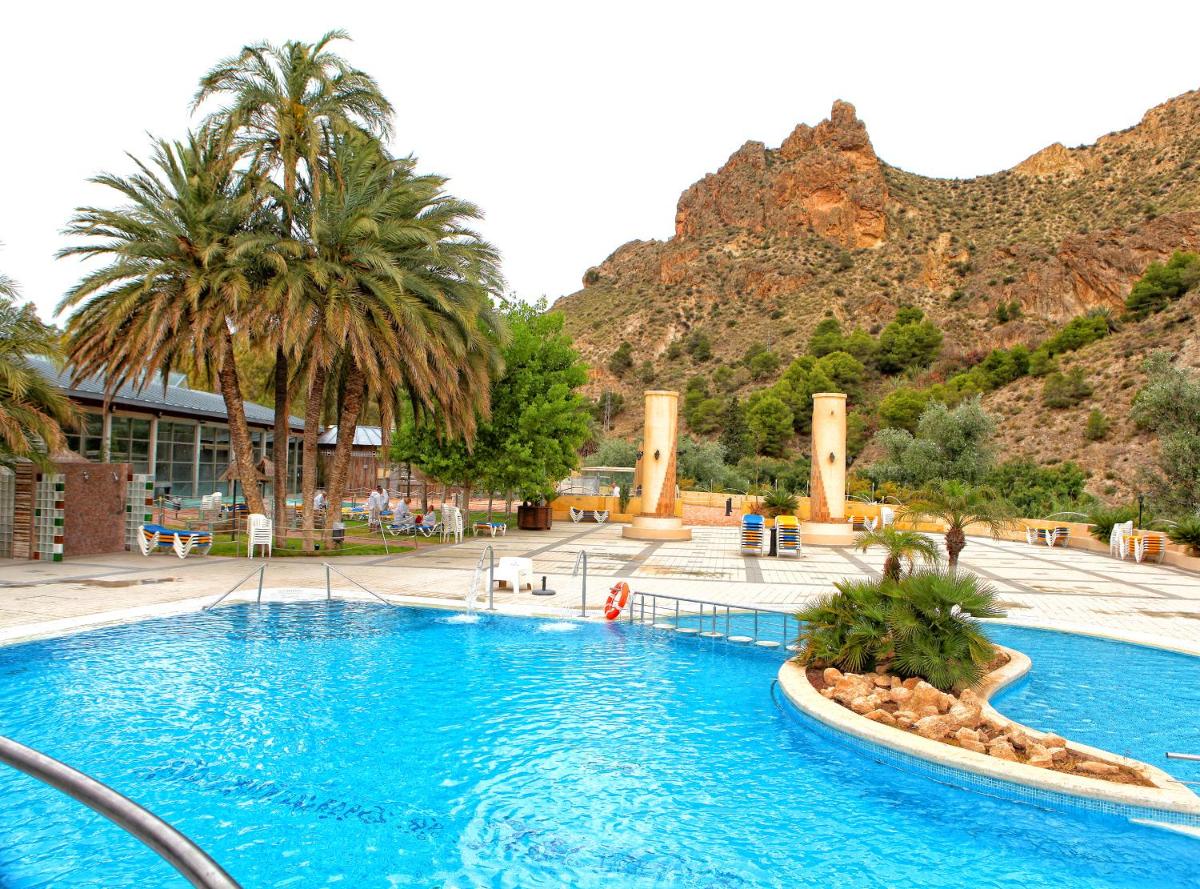 una gran piscina con palmeras y una montaña en Balneario de Archena - Hotel Termas, en Archena