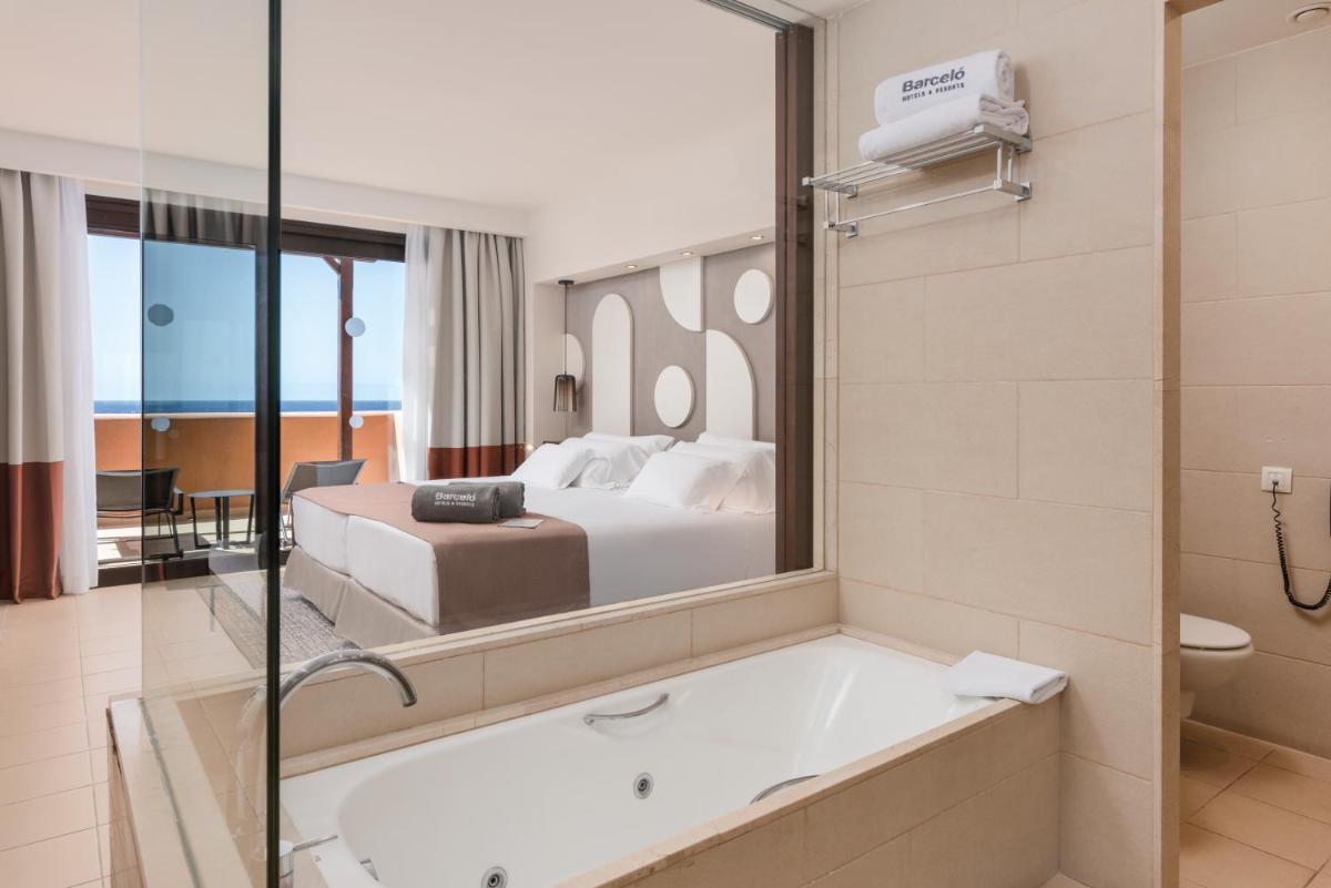 una habitación de hotel con bañera y cama en Barceló Tenerife Royal Level, en San Miguel de Abona