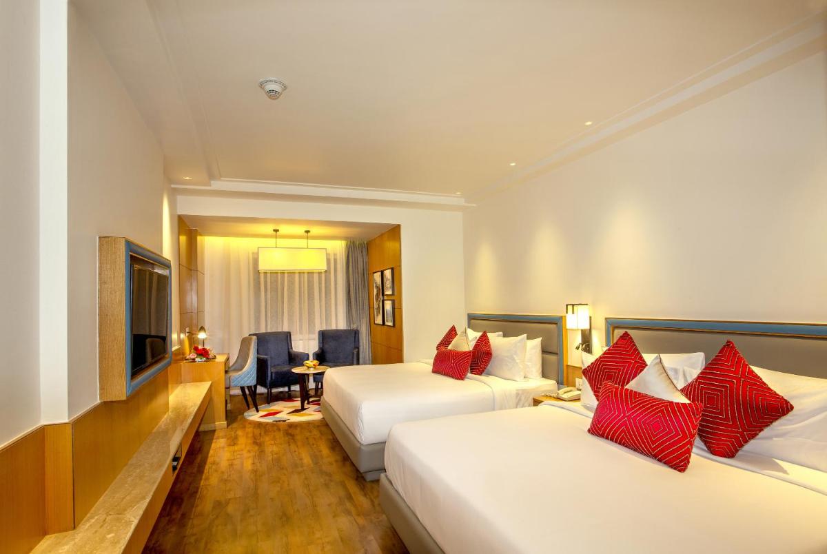 a hotel room with two beds with red pillows at Ramada by Wyndham Katra Station Road in Katra