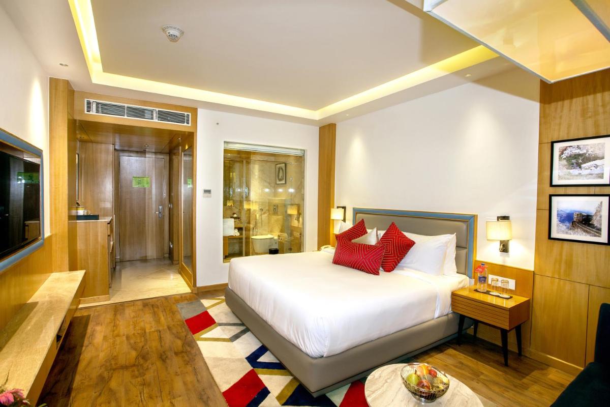 a bedroom with a white bed with red pillows at Ramada by Wyndham Katra Station Road in Katra