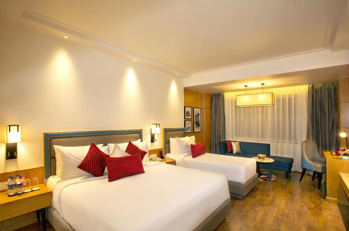 a hotel room with two beds and a desk at Ramada by Wyndham Katra Station Road in Katra