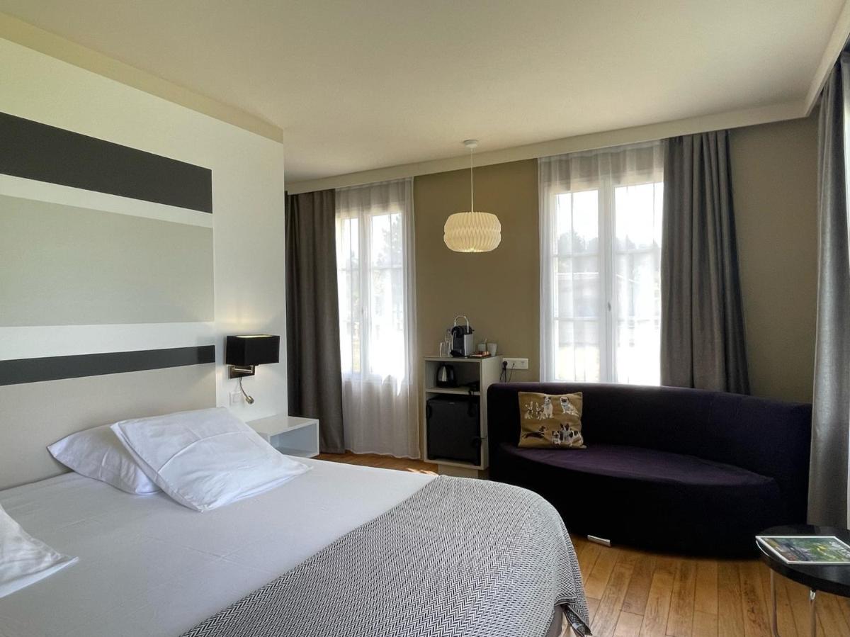 une chambre d'hôtel avec un lit et un canapé dans l'établissement Hôtel - Spa Les Corderies, à Saint-Valery-sur-Somme 55 autres photos