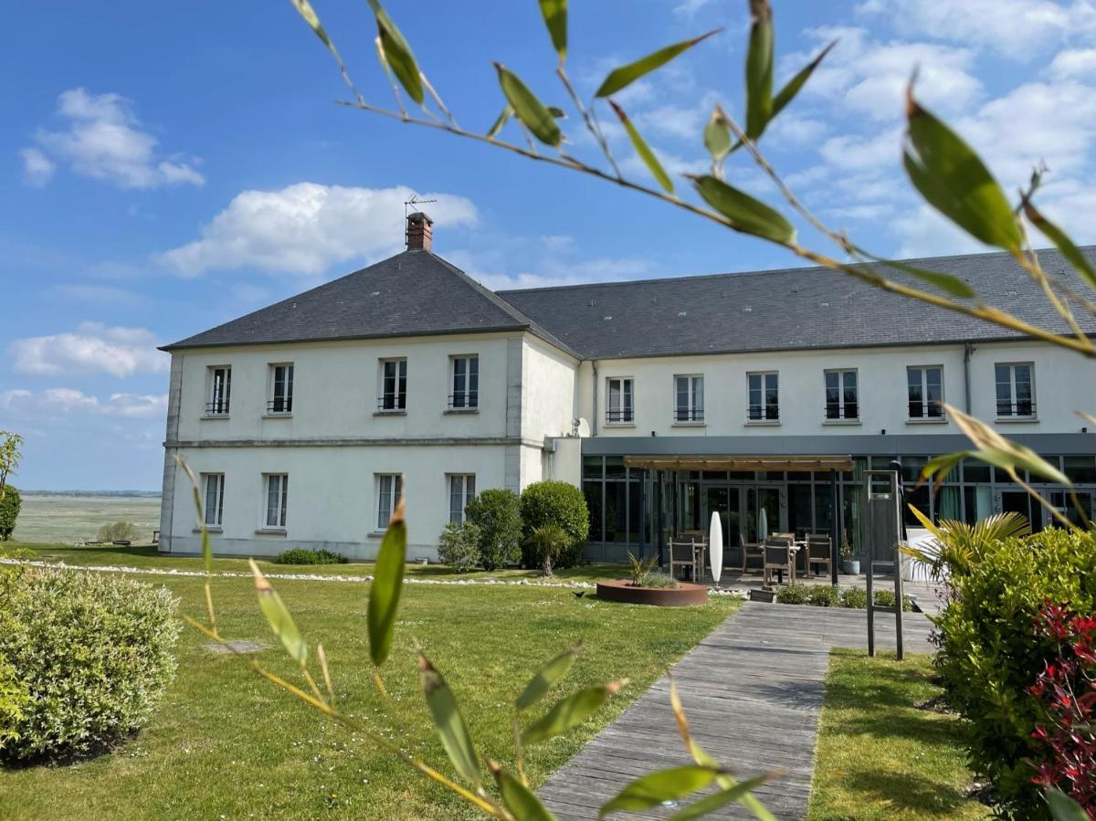 un grand bâtiment blanc avec une cour gazonnée dans l'établissement Hôtel - Spa Les Corderies, à Saint-Valery-sur-Somme