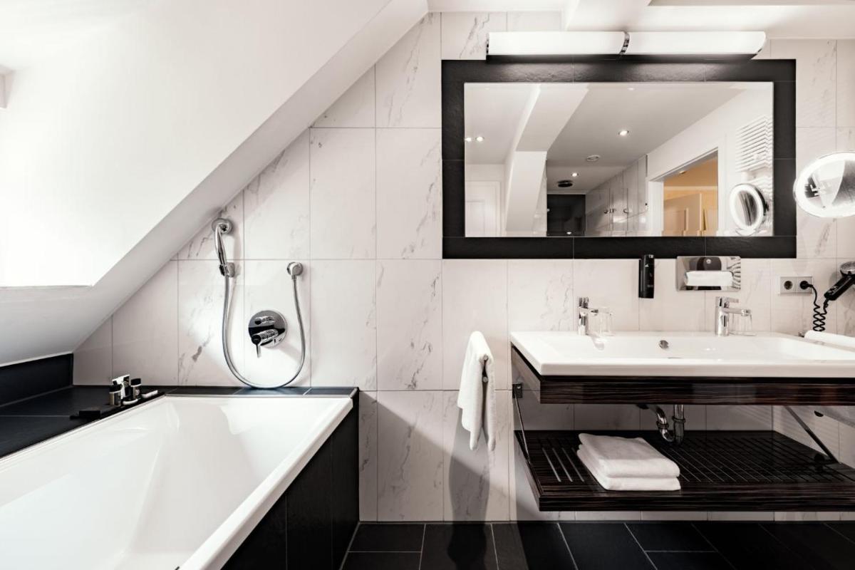 ein Badezimmer mit Badewanne, Waschbecken und Spiegel in der Unterkunft Burghotel Staufeneck in Salach + 37 Fotos