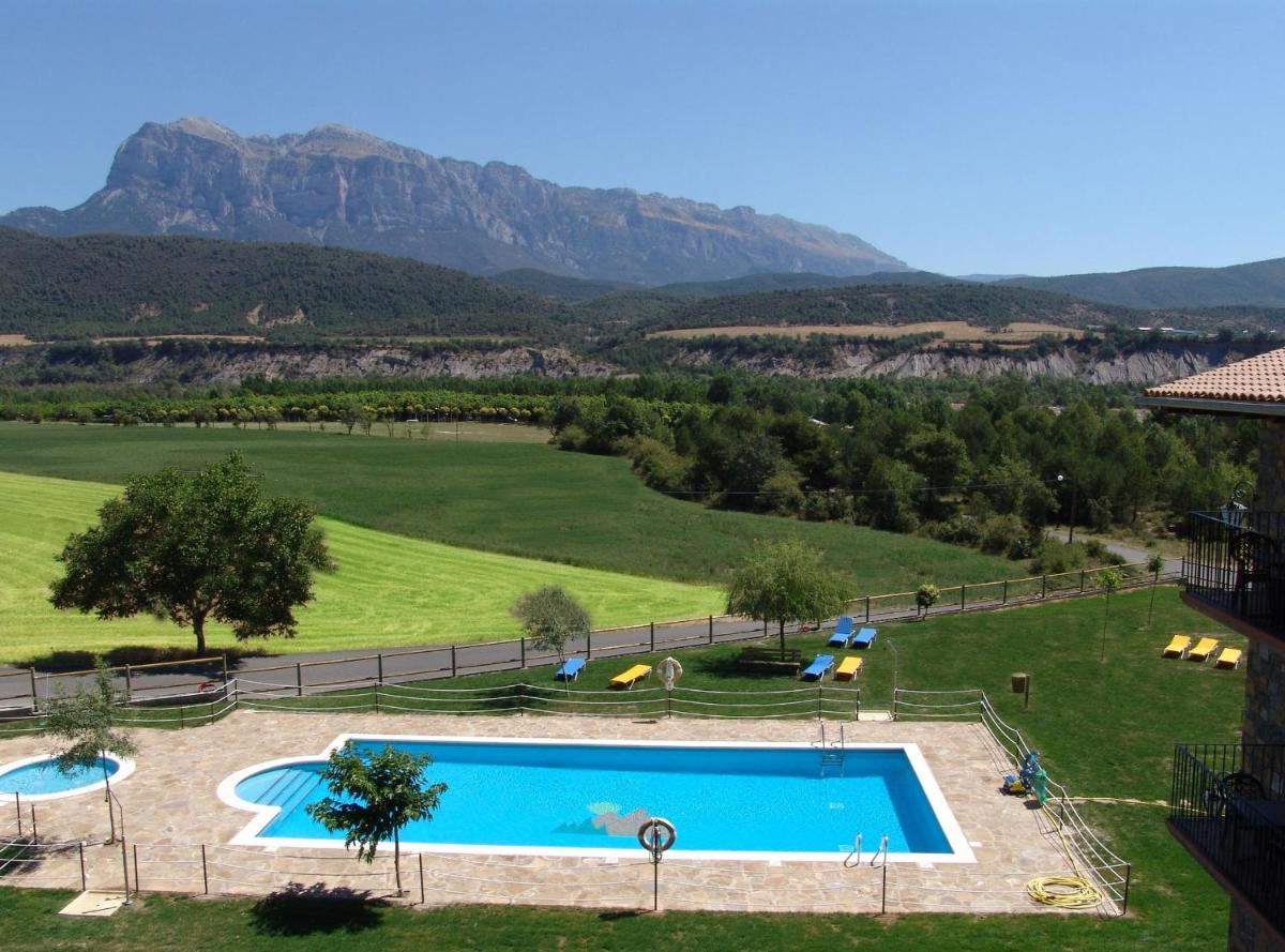 una piscina en un campo con montañas al fondo en Hotel & SPA Peña Montañesa, en Aínsa