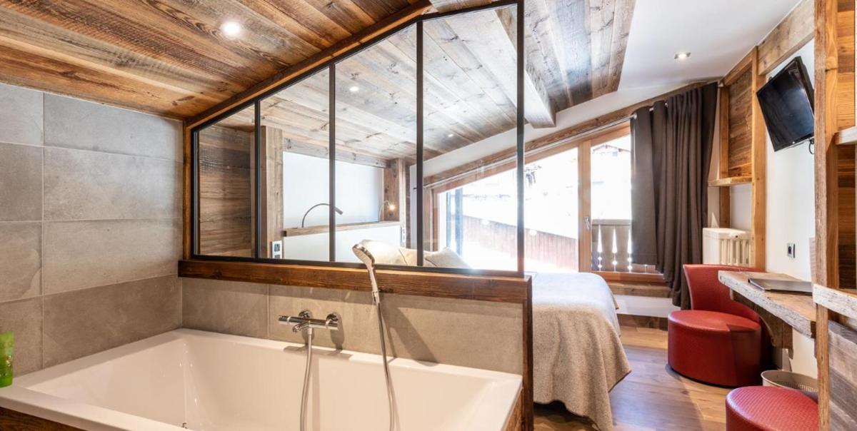 une salle de bains avec baignoire et une chambre avec un lit dans l'établissement Hotel le Petit Dru, à Morzine