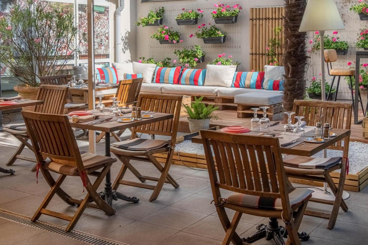 un restaurant avec des tables et des chaises en bois ainsi qu'un canapé dans l'établissement The Originals City, Hôtel Les Thermes de l'Avenue, Dax, à Dax