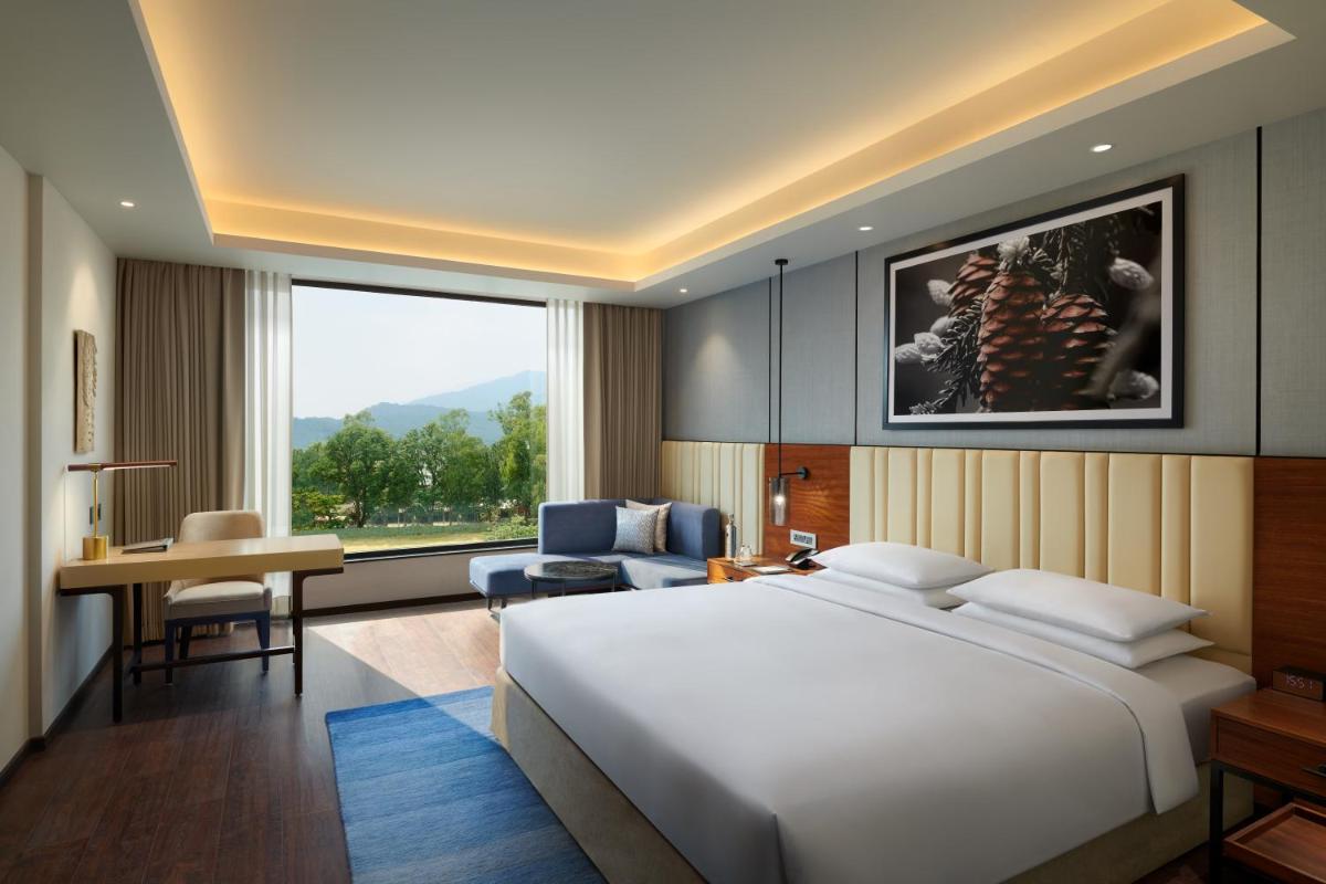 a bedroom with a large white bed and a desk at Hyatt Regency Dehradun Resort and Spa in Dehradun