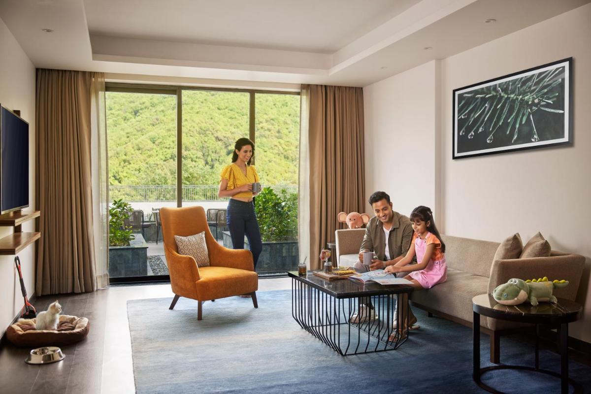 a woman standing in a living room with a family at Hyatt Regency Dehradun Resort and Spa in Dehradun