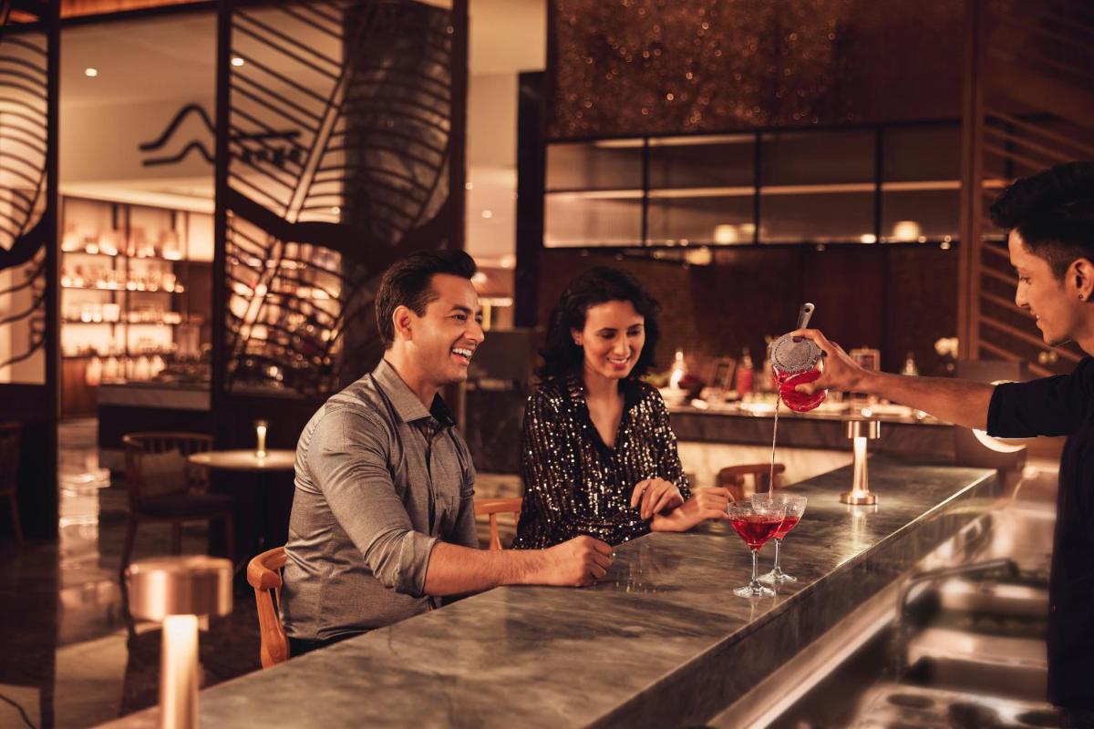 a group of people standing around a bar with a man pouring wine at Hyatt Regency Dehradun Resort and Spa in Dehradun