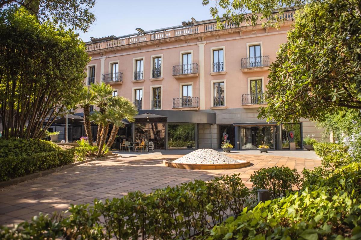 Un gran edificio rosa con un patio. en RVHotels Spa Vila de Caldes - Adults only, en Caldes de Montbui