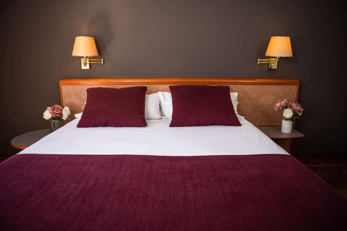 Un dormitorio con una cama grande con sábanas y almohadas moradas. en RVHotels Spa Vila de Caldes - Adults only, en Caldes de Montbui