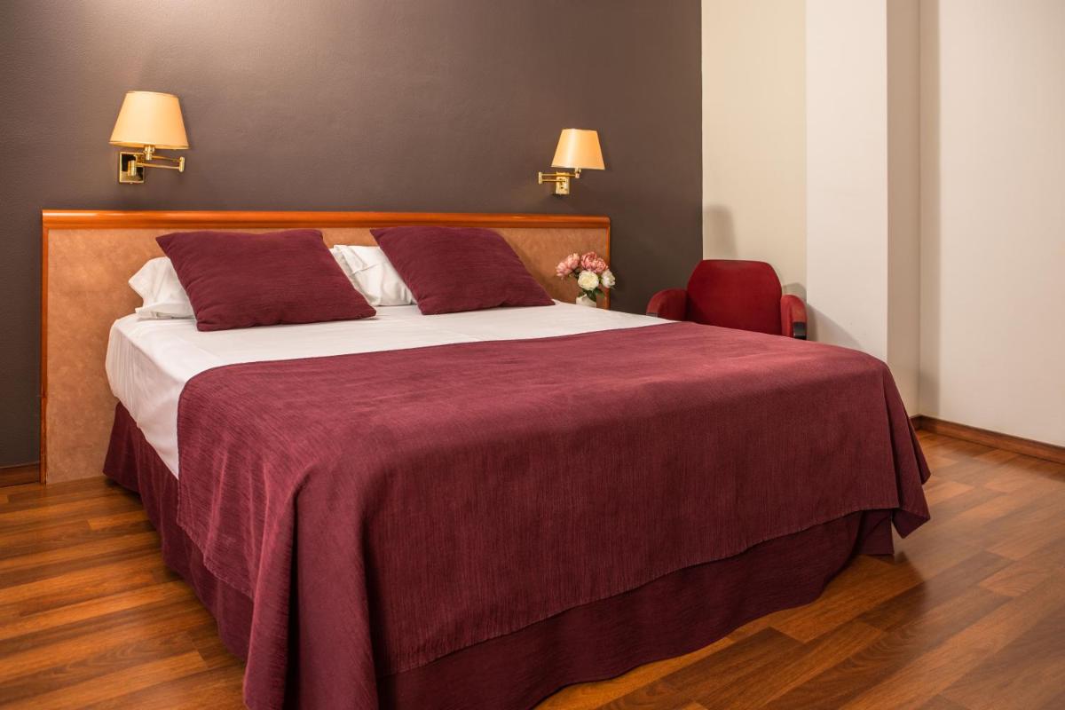 Un dormitorio con una cama grande y una silla roja. en RVHotels Spa Vila de Caldes - Adults only, en Caldes de Montbui