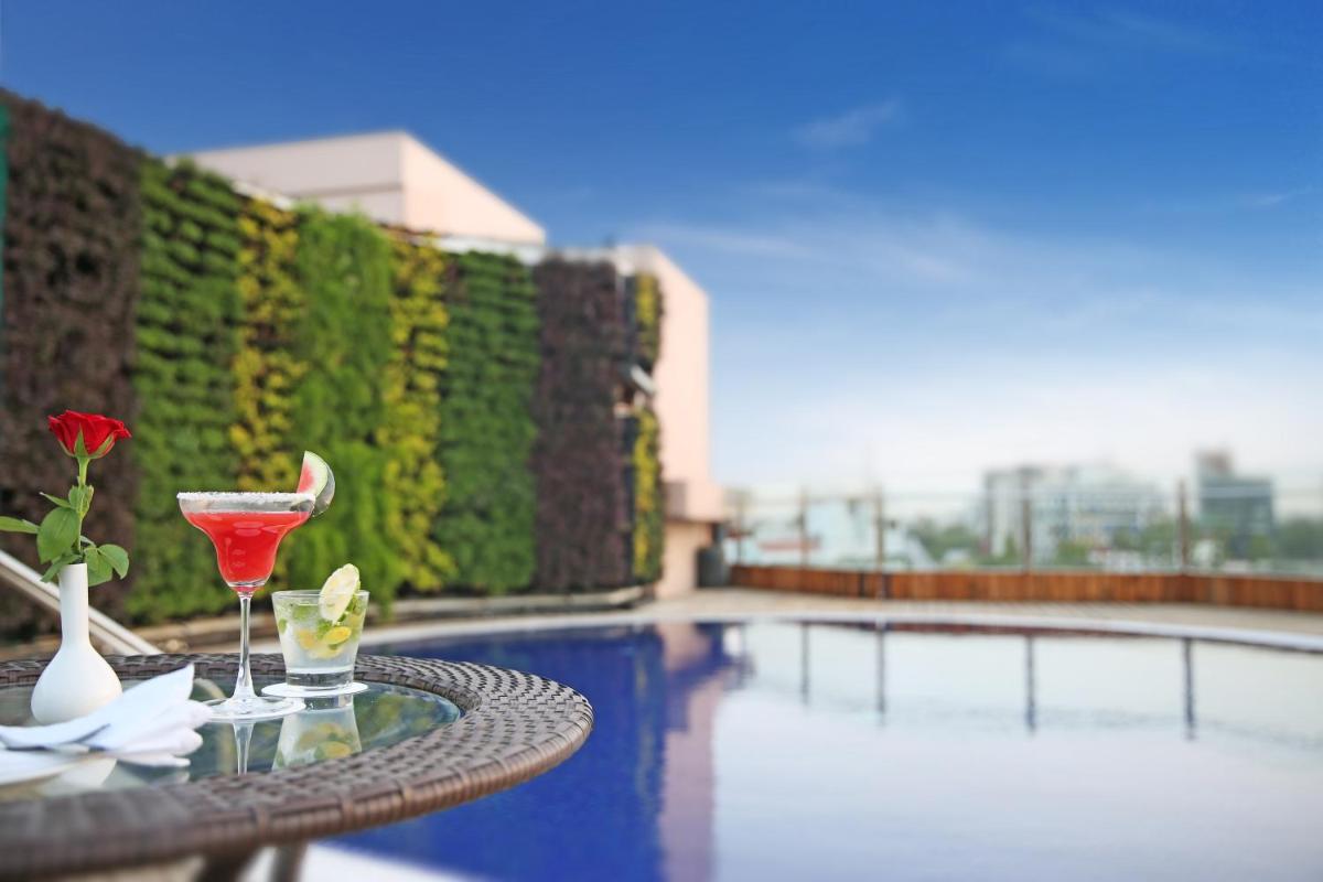 a table with a martini and a drink on it next to a pool at Golden Tulip Jaipur in Jaipur