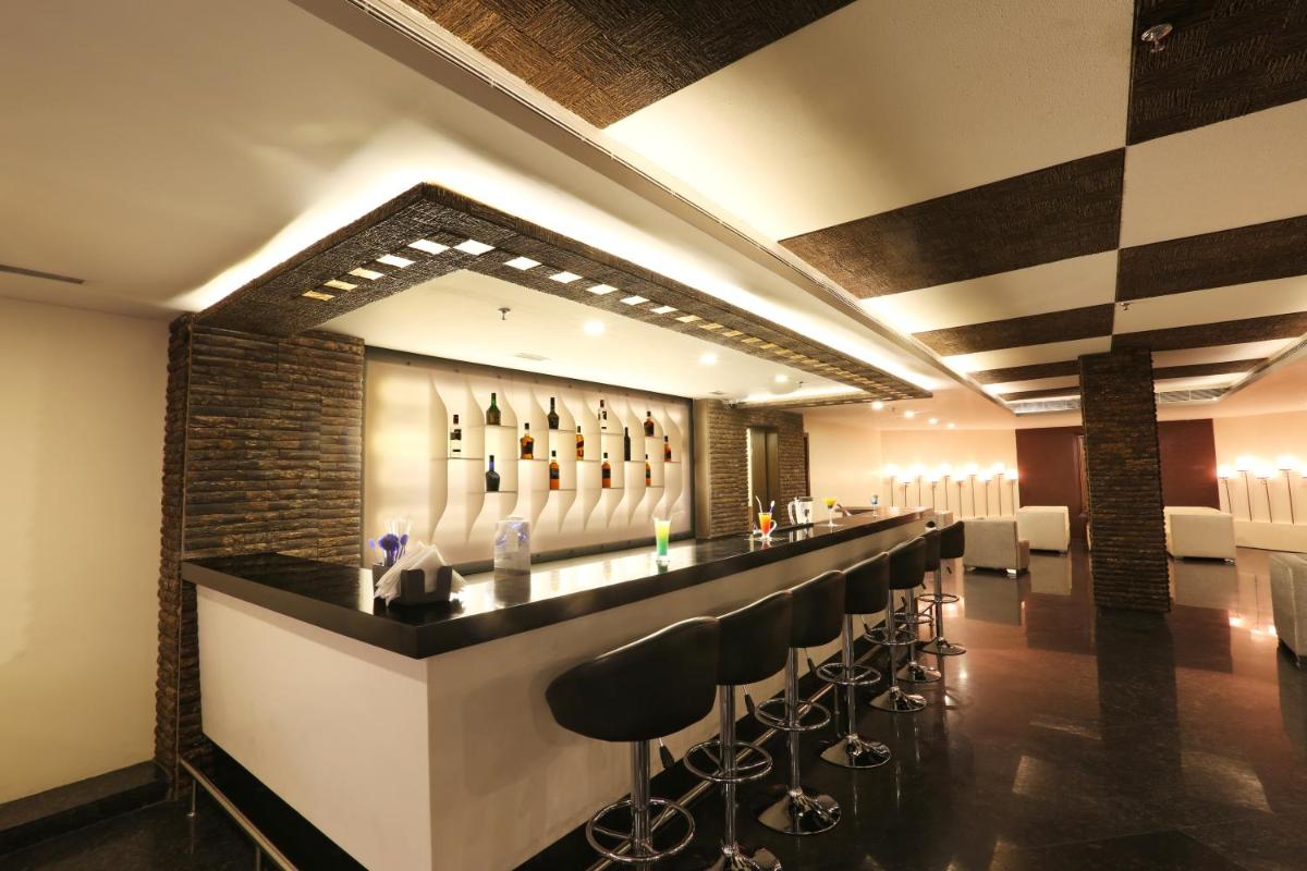 a bar with a row of stools in a room at Golden Tulip Jaipur in Jaipur