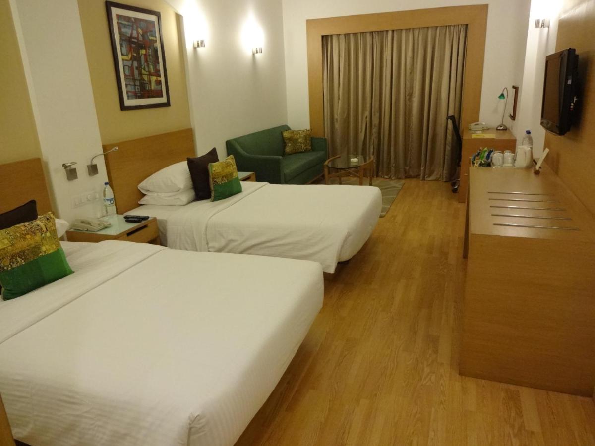 a hotel room with two beds and a couch at Lemon Tree Premier Hitec City Hyderabad in Hyderabad