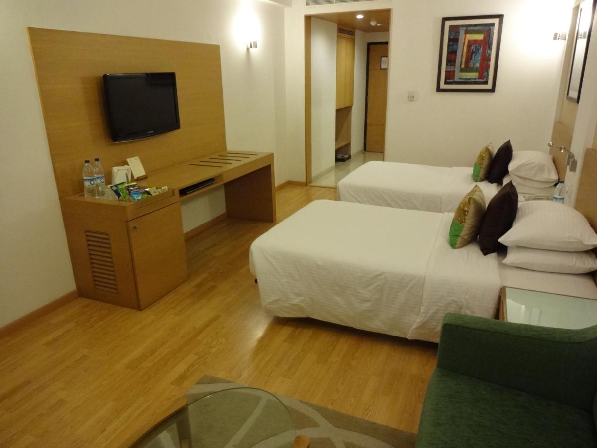 a hotel room with two beds and a desk at Lemon Tree Premier Hitec City Hyderabad in Hyderabad