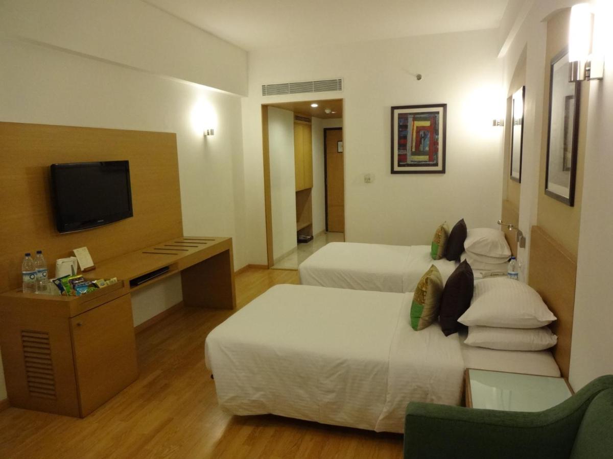 a hotel room with two beds and a television at Lemon Tree Premier Hitec City Hyderabad in Hyderabad