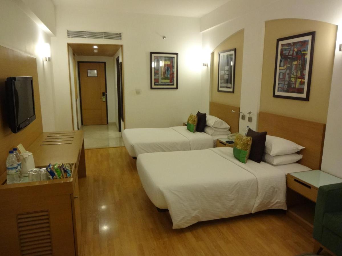a hotel room with two beds and a flat screen tv at Lemon Tree Premier Hitec City Hyderabad in Hyderabad
