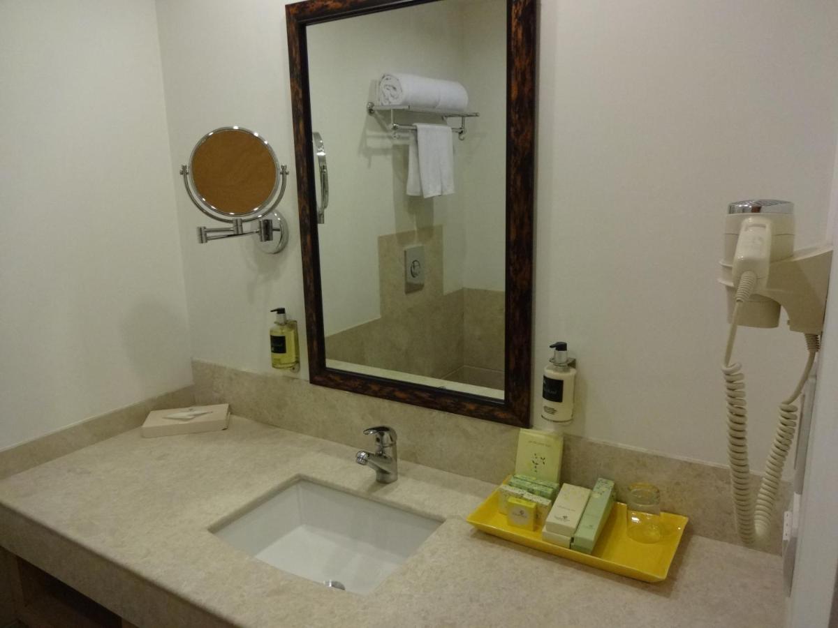 a bathroom with a sink with a mirror and a phone at Lemon Tree Premier Hitec City Hyderabad in Hyderabad