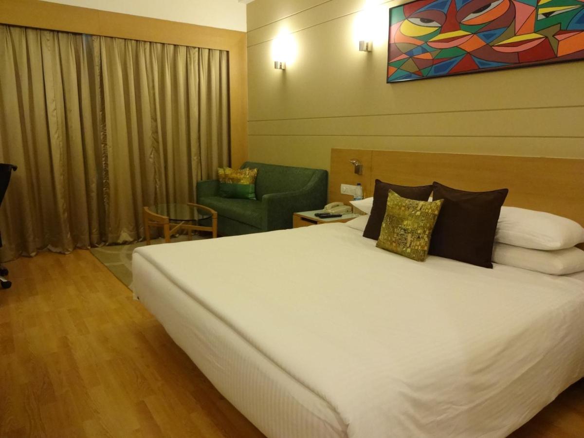 a hotel room with a large bed and a chair at Lemon Tree Premier Hitec City Hyderabad in Hyderabad