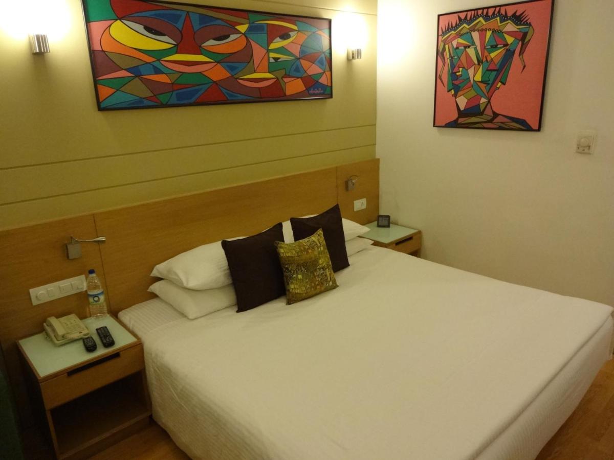 a bedroom with a white bed with a painting on the wall at Lemon Tree Premier Hitec City Hyderabad in Hyderabad