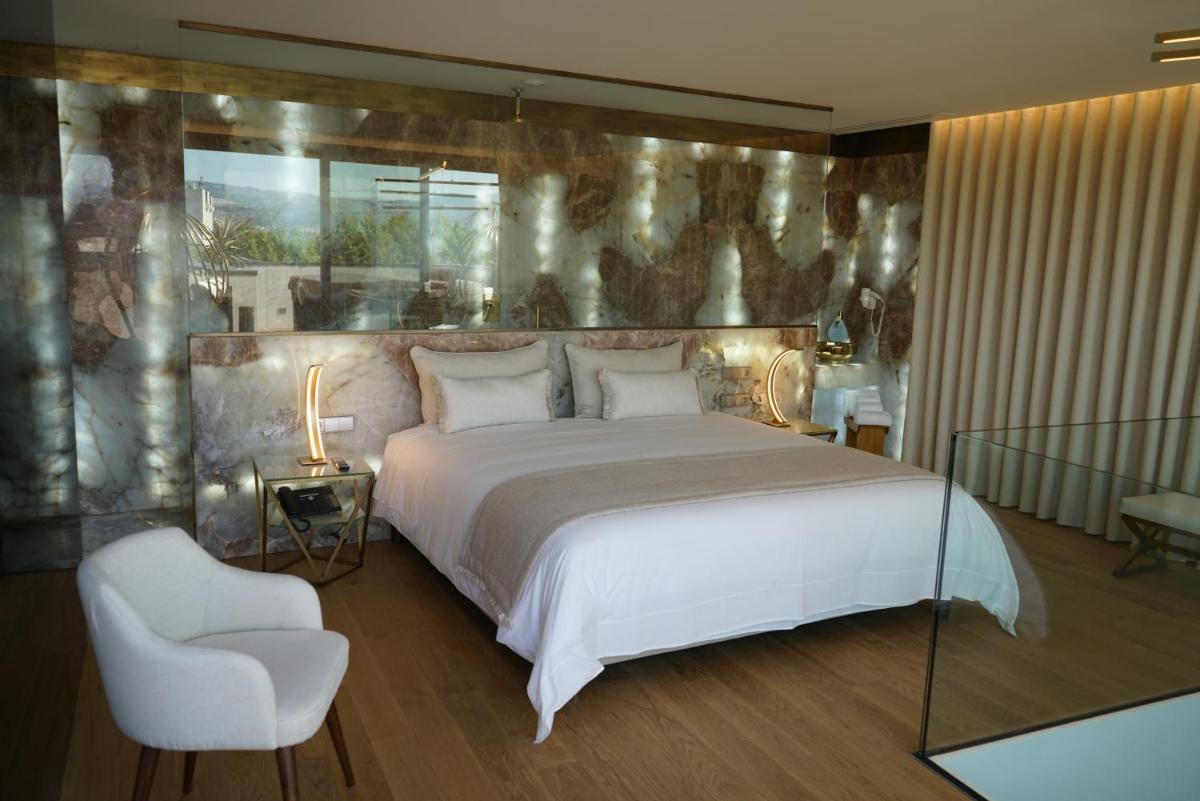 um quarto com uma grande cama branca e uma cadeira em Castelo Hotel em Chaves mais 67 fotografias