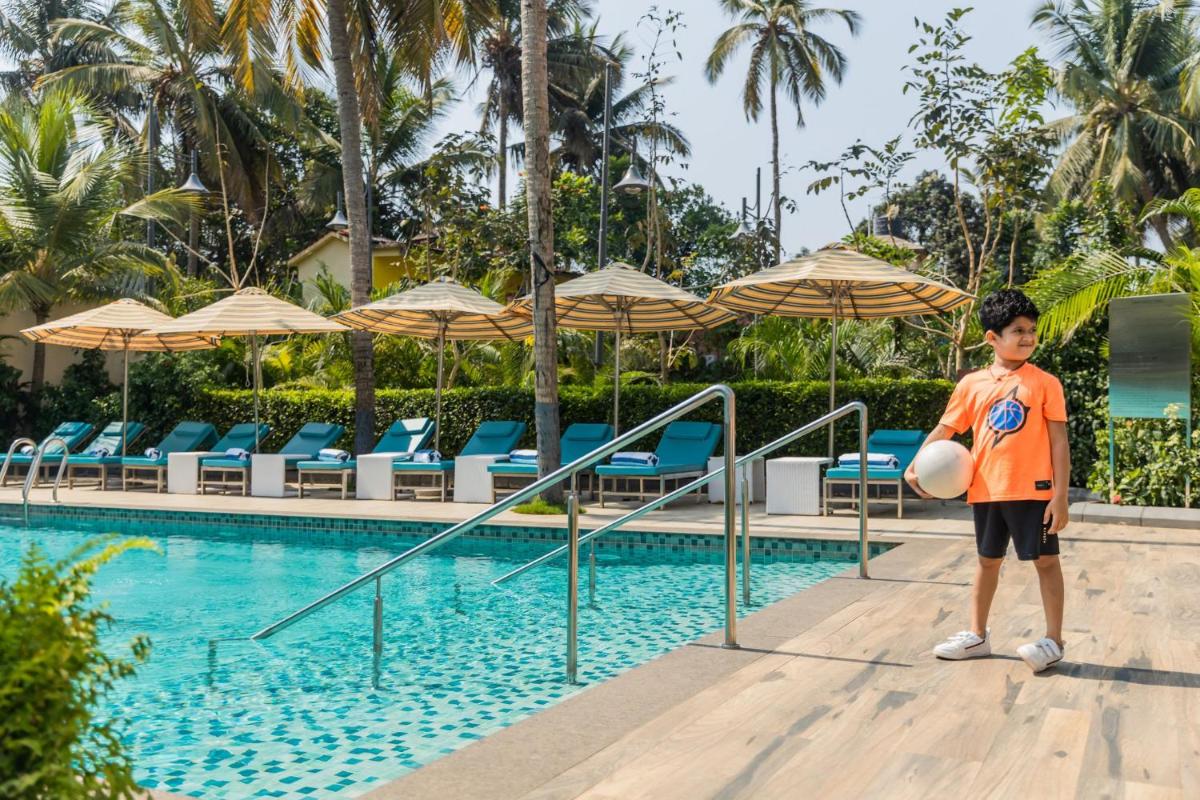 a young boy standing next to a swimming pool at Holiday Inn Goa Candolim in Candolim a young boy standing next to a swimming pool at Holiday Inn Goa Candolim in Candolim