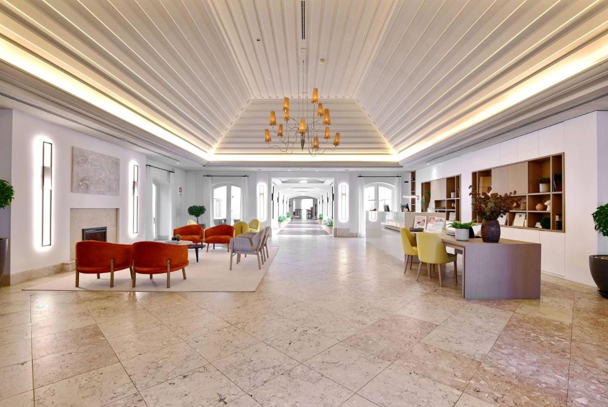 uma sala de estar ampla com um lustre, mesas e cadeiras. em Dolce CampoReal Lisboa em Turcifal