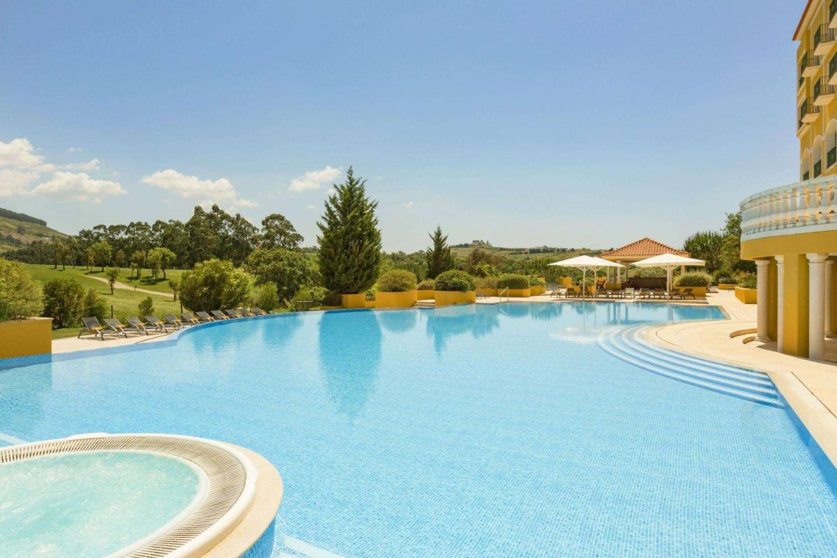 uma grande piscina em um resort com cadeiras em Dolce CampoReal Lisboa em Turcifal