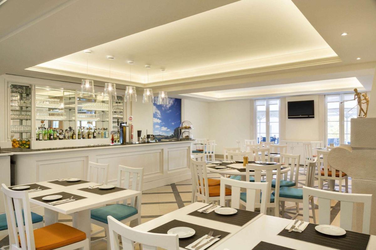 um restaurante com mesas e cadeiras brancas e um bar em Dolce CampoReal Lisboa em Turcifal