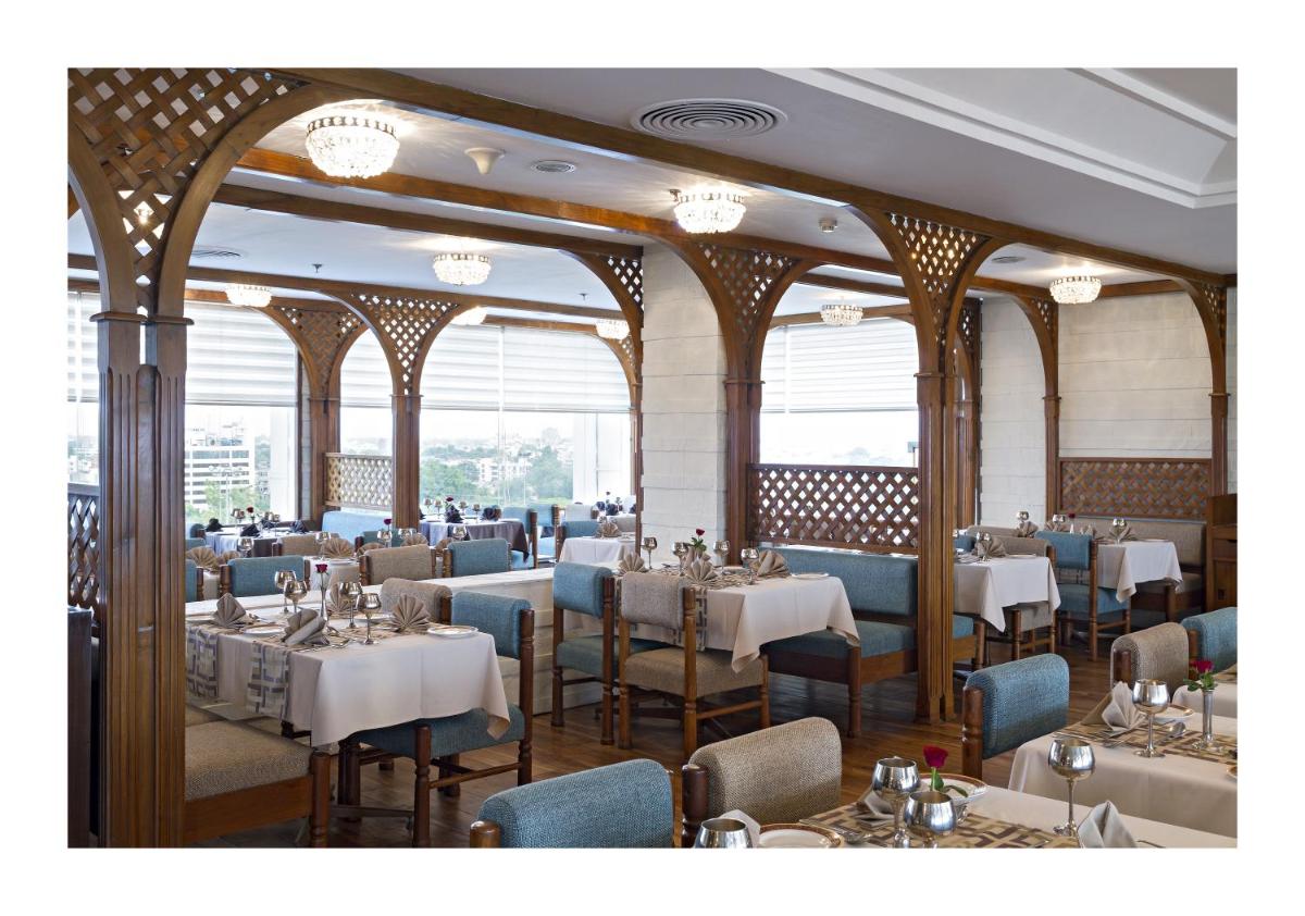 a restaurant with tables and chairs in a room at Clarks Avadh in Lucknow