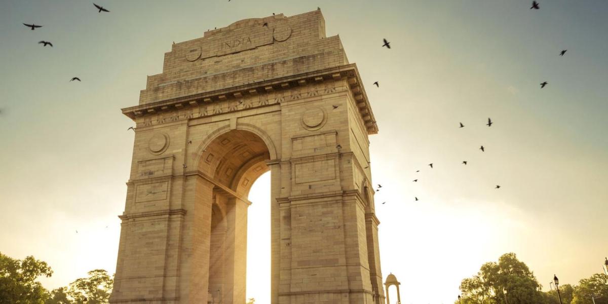 a clock tower with birds flying around it at Crowne Plaza New Delhi Okhla by IHG in New Delhi