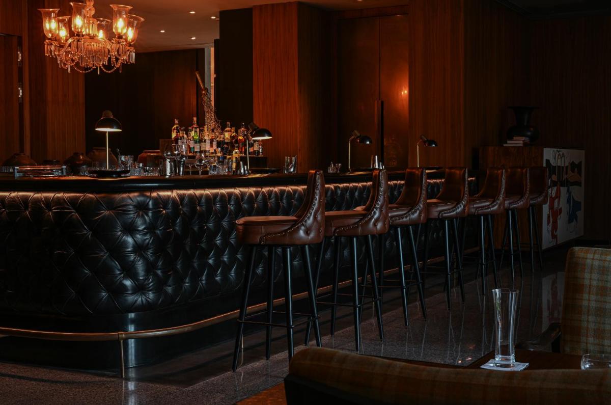 a bar with a row of brown leather stools at Grand Hyatt Gurgaon in Gurgaon